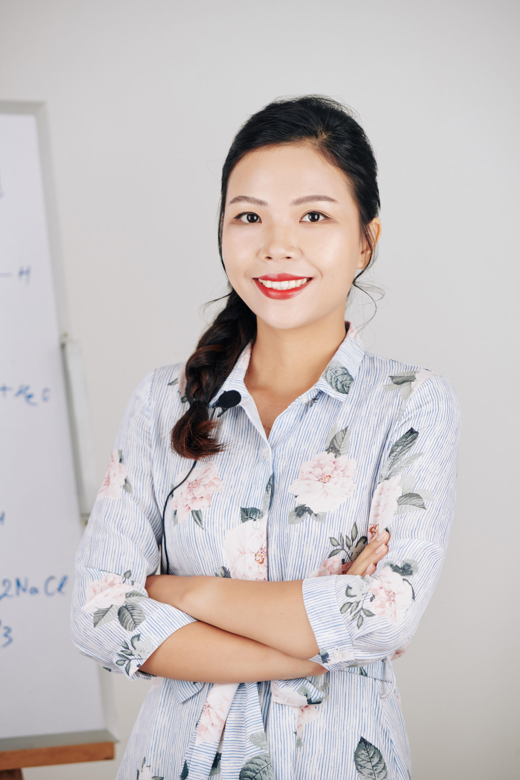 Portrait of pretty smiling Vietnamese science teacher standing with arms crossed